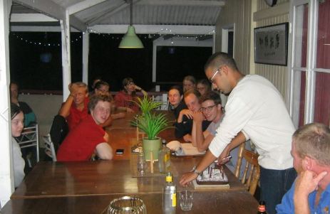 Group of people at the dinner table waiting for a cake to be cut 