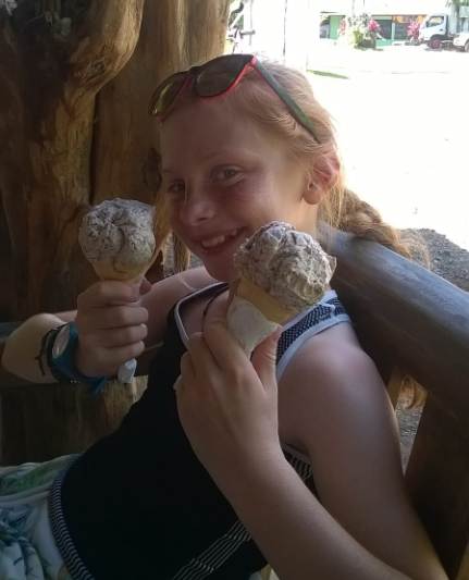 Girl holding two ice creams and smiling at the camera