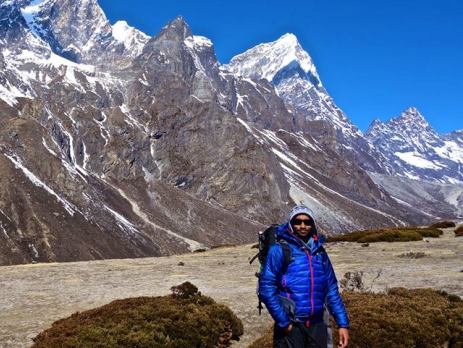 Hiker smiling at the camera in front of a backdrop of mountains in Nepal 