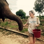 Volunteer walks with an elephant at the sanctuary in Thailand