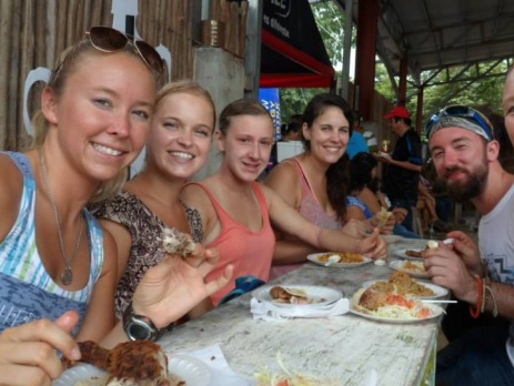 A group of smiling volunteers enjoying a traditional lunch in Costa Rica in a cafe. 