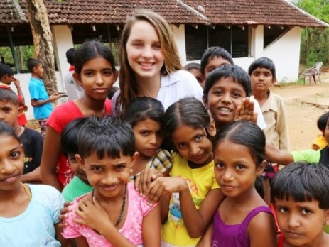 Volunteer in Sri Lanka with lots of colourful Sri Lankan school children smiling at the camera in a group shot 