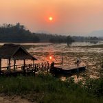 The sun sets and reflects in the lake at the elephant sanctuary in Laos