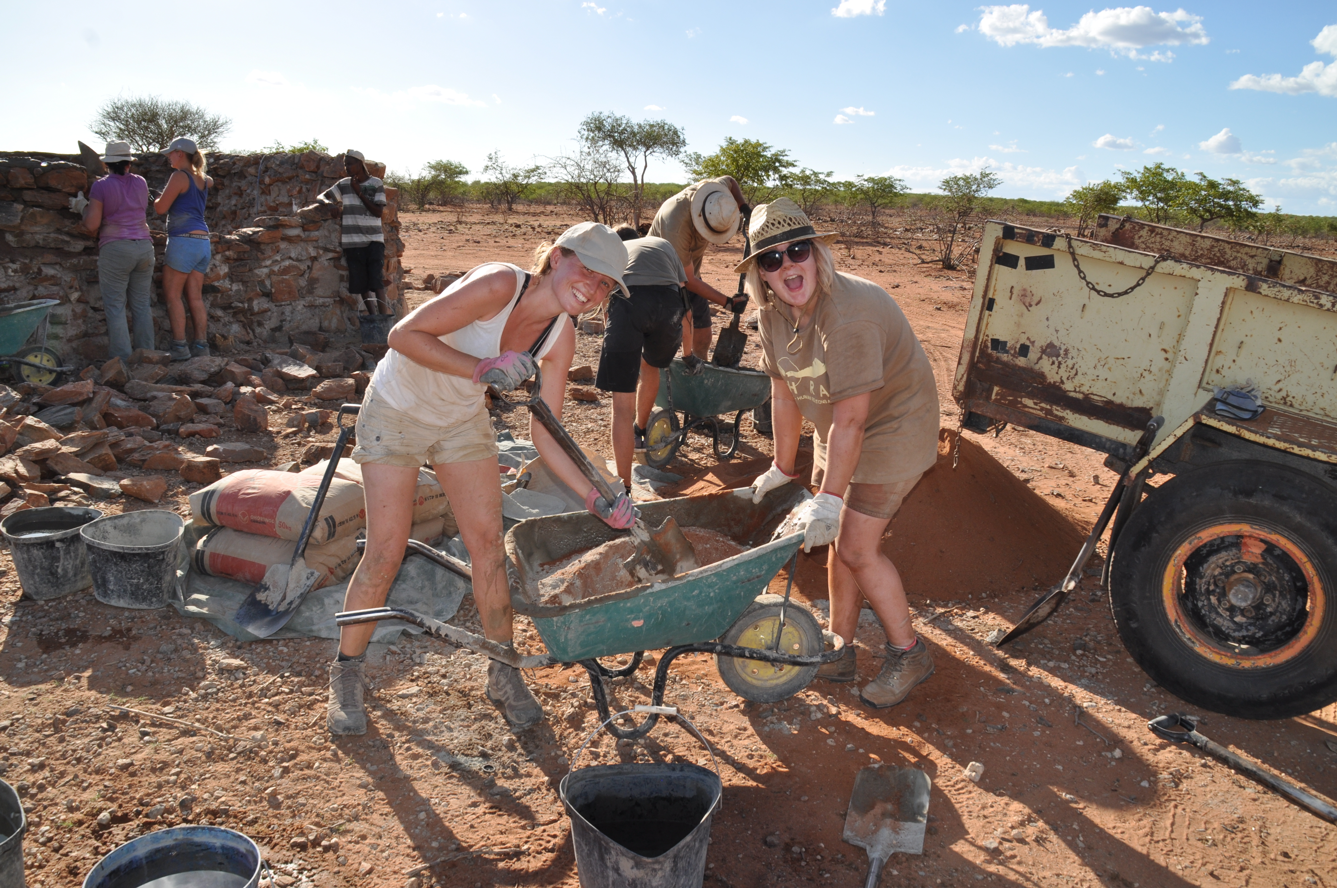 Two enthusiastic volunteers mixing cement in the Namibian desert 