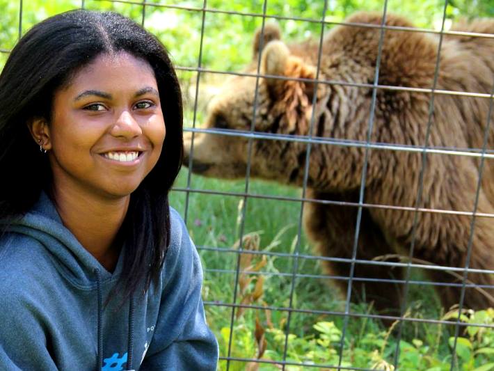 A volunteer poses with a bear at the bear sanctuary in Romania