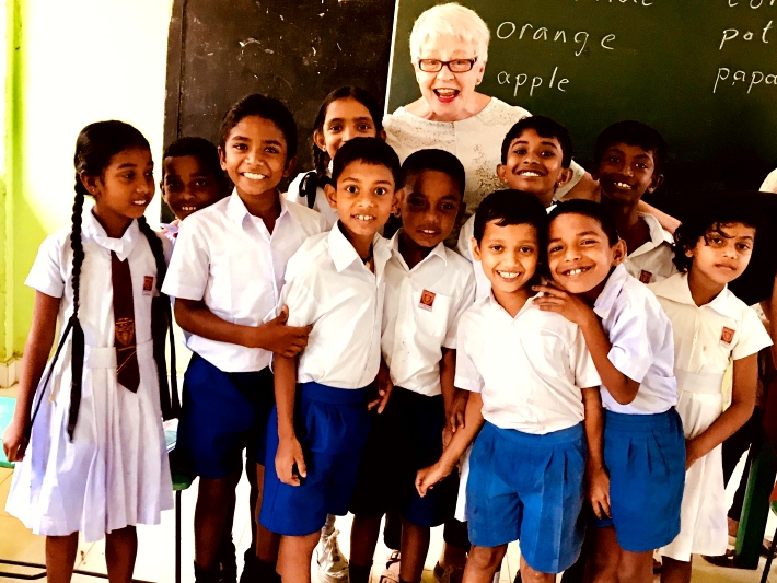 A volunteer teaches English to children in a school in Sri Lanka