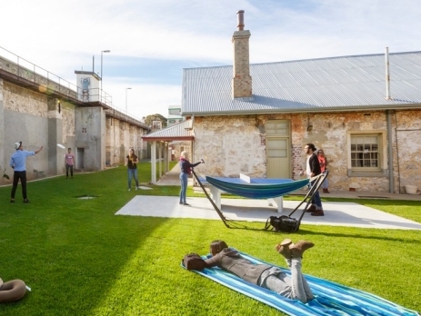 View from the communal outside area at Freemantle prison YHA in Western Australia. Backpackers enjoying the hammocks and playing games in the sunshine. 