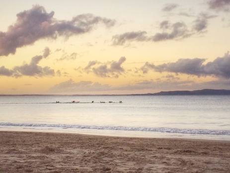 Sunset beach scene at Noosa's main beach with kayakers in the distance 