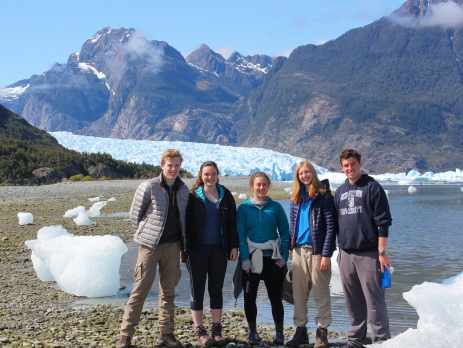 A group of British and American gap year volunteers in Chile, standing in front of a glacier and a mountain. 